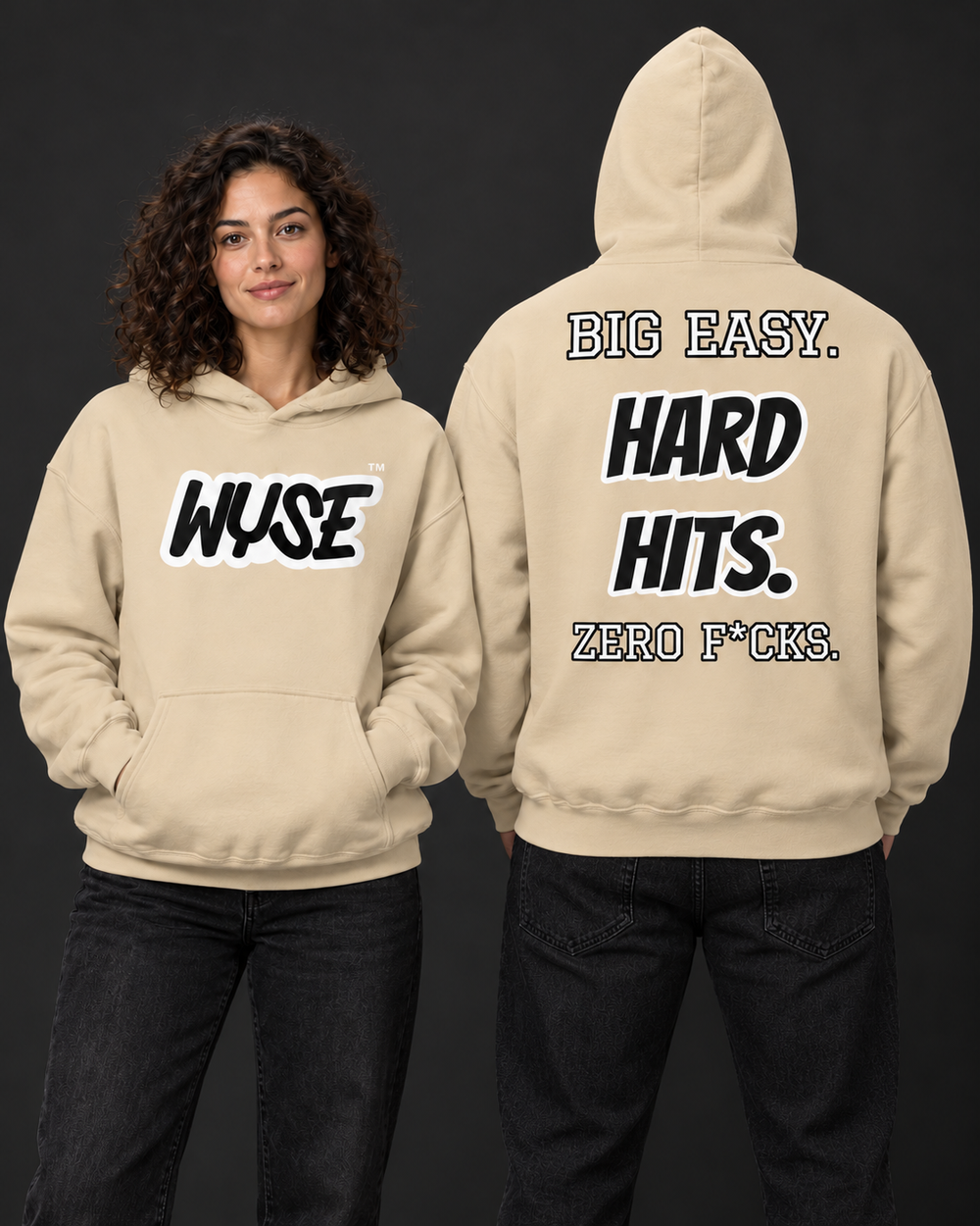 WYSE New Orleans Saints fan hoodie in sand, woman showing black WYSE front logo and athletic man facing fully away with Big Easy Hard Hits back print.